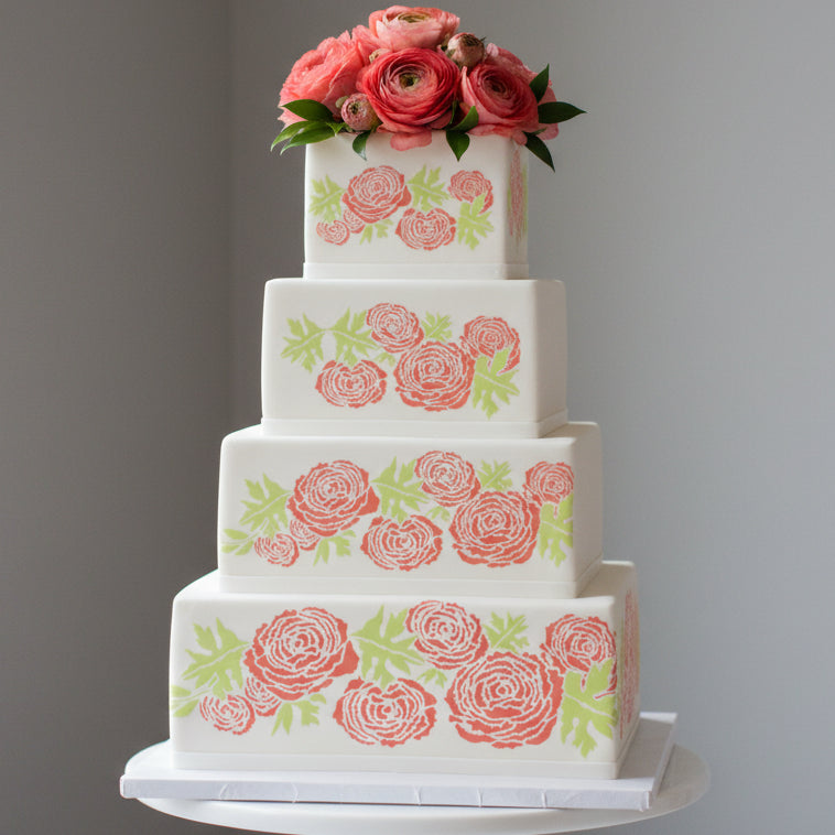 Decorative design of stylized flowers and leaves in coral and green on a white cake