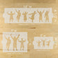 Set of three graduation cake stencils with dancing figures and measurements on a wooden surface