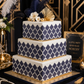 Three-tiered cake with navy geometric pattern on a decorative background
