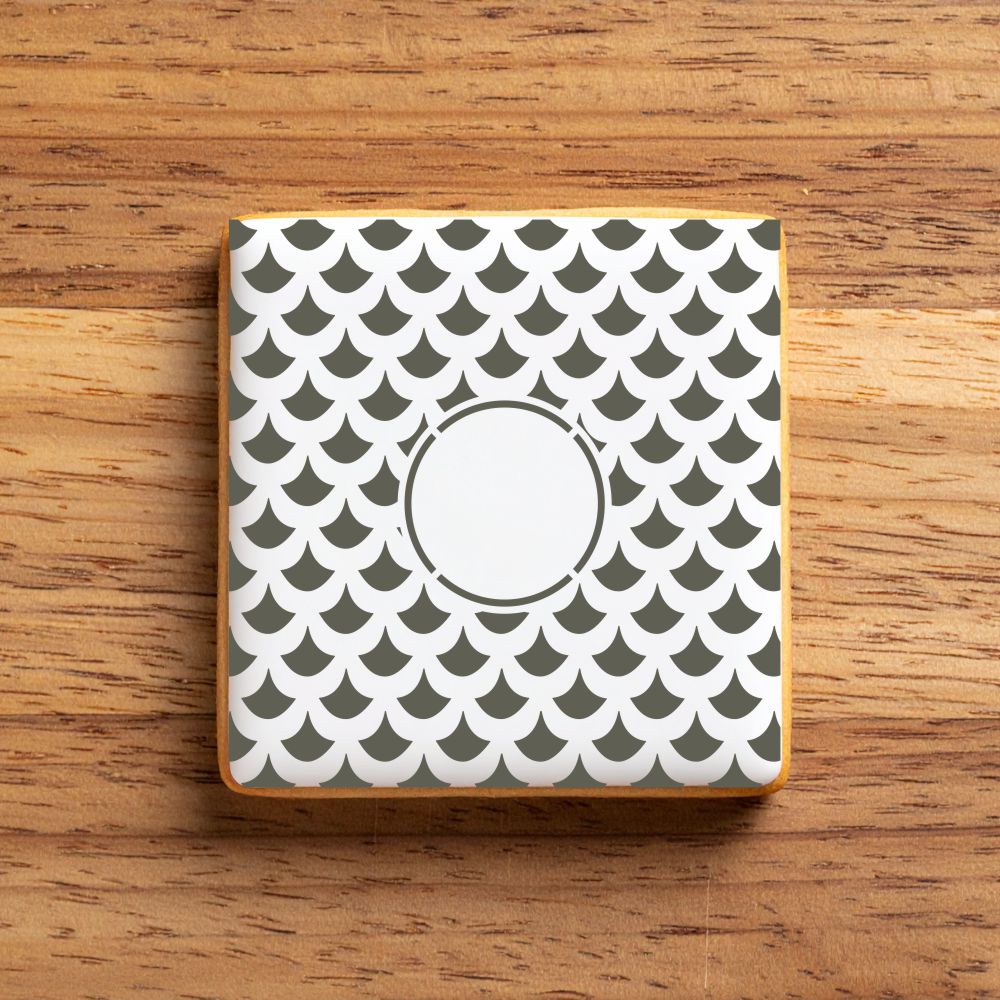 Square iced cookie stenciled with a scale pattern on a wooden surface