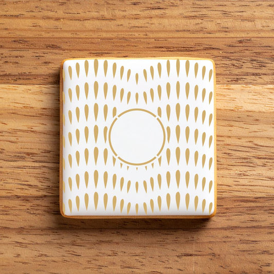 White iced cookie stenciled with a gold pattern.