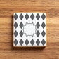 Square iced cookie with gray diamond pattern on a wooden surface