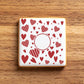 Square cookie stenciled with a red heart pattern