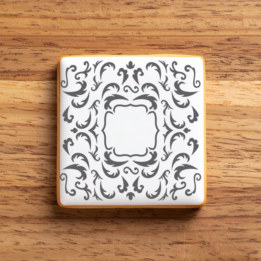 Decorative square cookie with intricate black pattern on a wooden surface