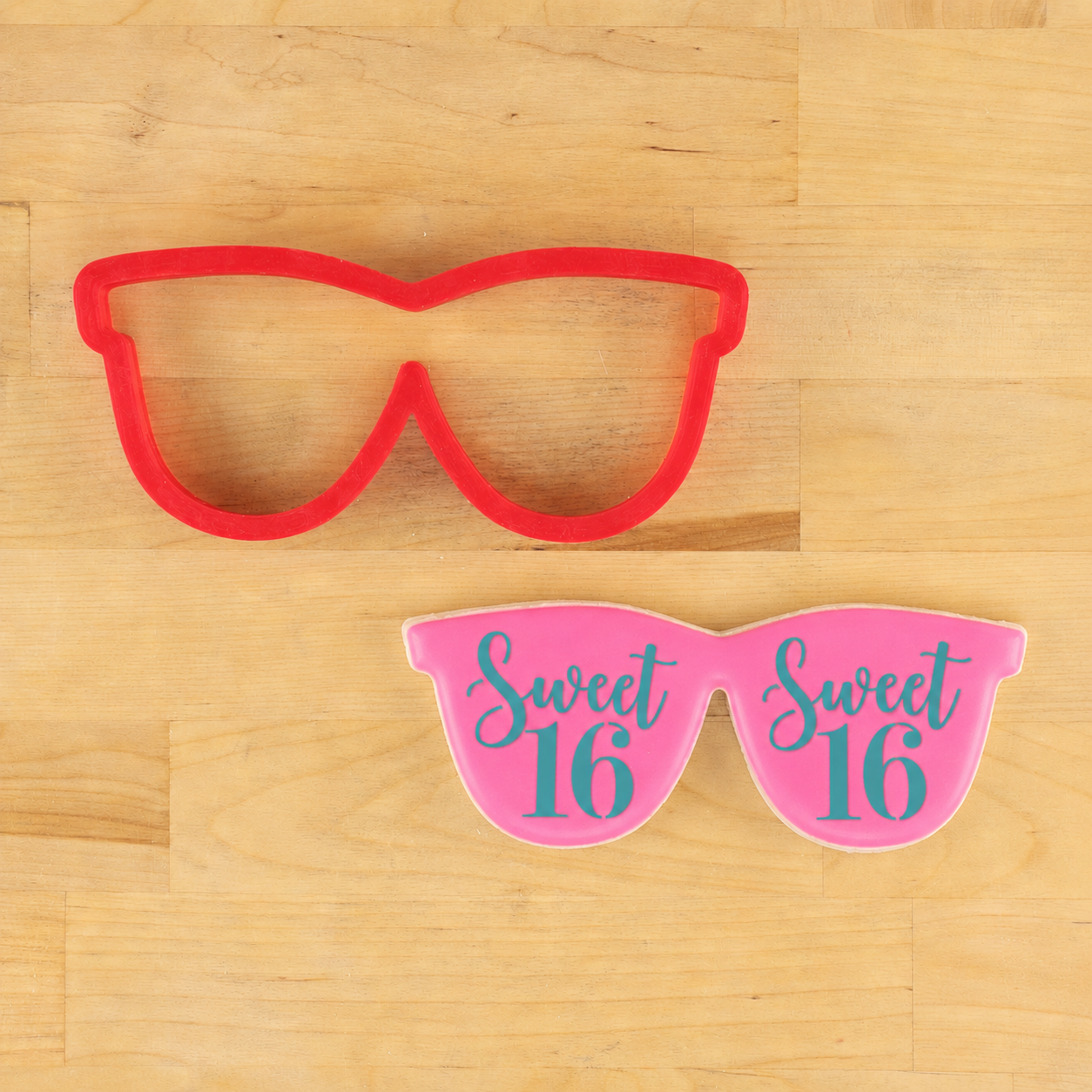 Red and pink 'Sweet 16' sunglasses on a wooden surface