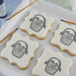 Four large plaque style cookies, flooded with white royal icing, and stenciled with the Easter Basket Paint Your Own Cookie Stencils. 