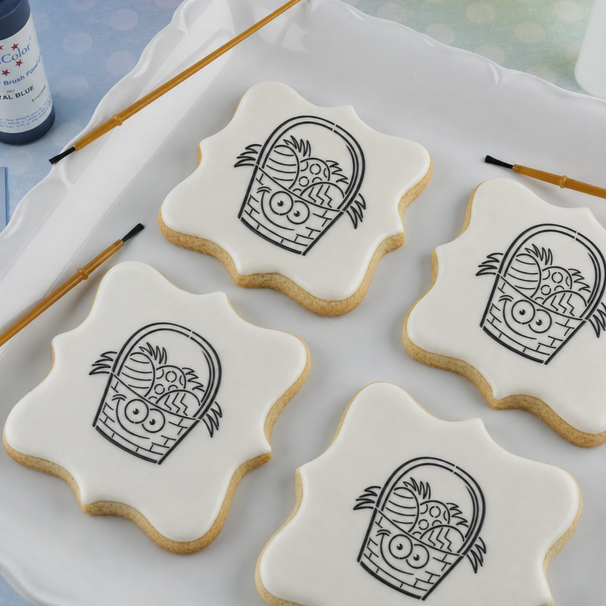 Four large plaque style cookies, flooded with white royal icing, and stenciled with the Easter Basket Paint Your Own Cookie Stencils. 