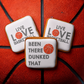 Three square iced cookies with basketball-themed quotes are arranged on top of a red basketball. The cookies have white icing borders and centers with gray text and an orange basketball graphic.