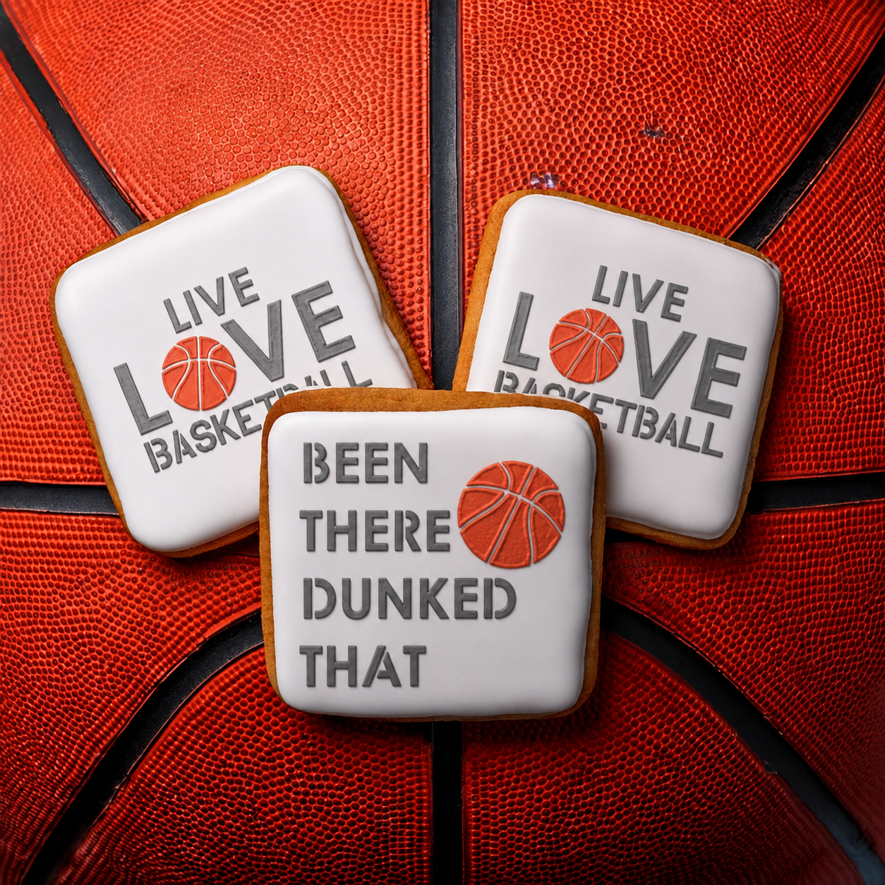 Three square iced cookies with basketball-themed quotes are arranged on top of a red basketball. The cookies have white icing borders and centers with gray text and an orange basketball graphic.
