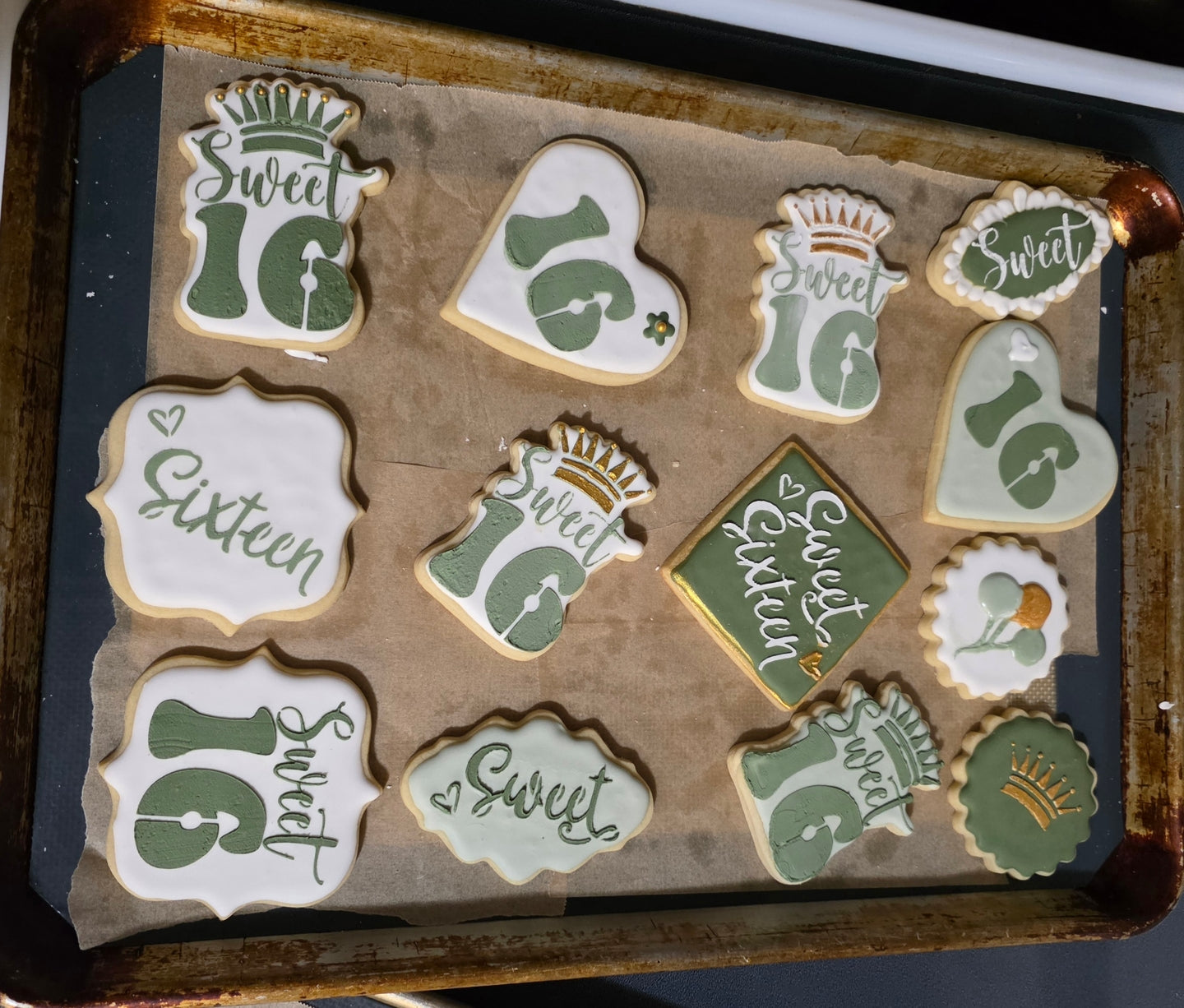 Decorative cookies with 'Sweet 16' designs on a baking tray.