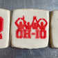 Three cookies with Ohio State-themed designs on a metal surface