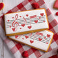 Musical themed cookies decorated with sheet music and hearts, perfect for Valentine's Day treats.