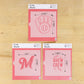 Three pink cookie stencils with measurements on a wooden surface