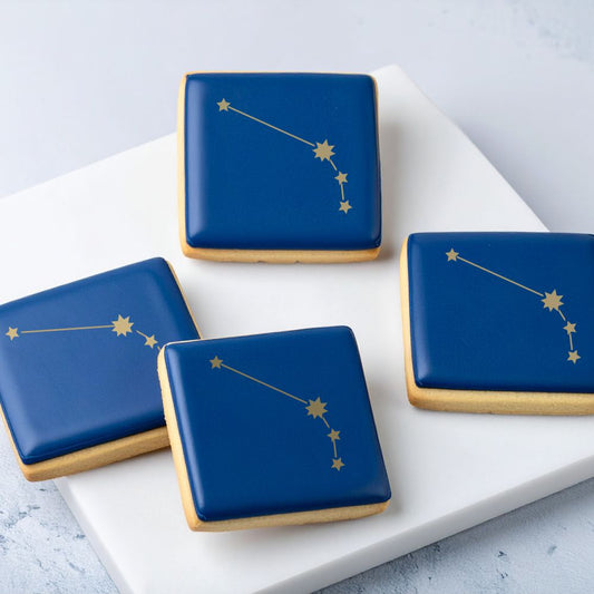 Cookies with blue icing and stenciled gold Aries star constellation.