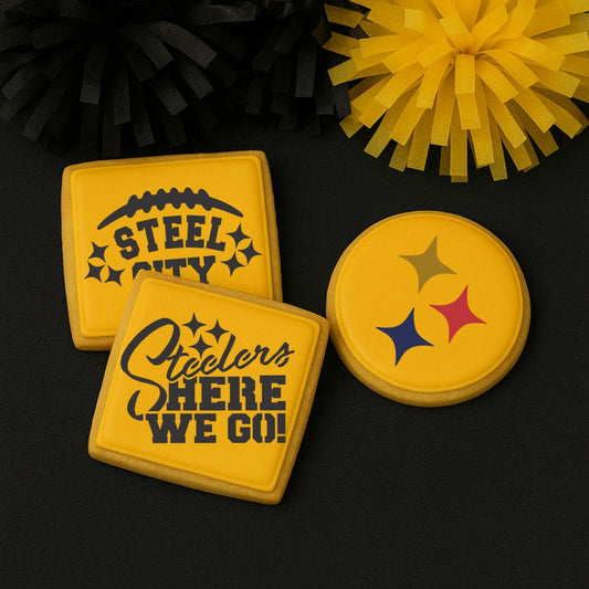 three yellow iced cookies with Steelers-themed designs airbrushed on them laying on a black background