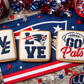 White iced cookies with Patriots-inspired designs on a tablecloth with sports team logos