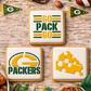 Three square iced cookies decorated with Green Bay Packers themes are arranged on a rustic wooden table. One cookie says 'GO PACK GO' with yellow and green stripes, one shows the Packers 'G' logo with 'PACKERS' underneath, and one features a slice of cheese with holes.