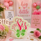 Decorated Little Sis sugar cookie displayed at a Big/Little Reveal celebration with pink and green décor, flowers, and sorority-themed decorations.