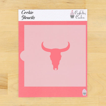 A pink cookie stencil sheet with a bull skull cutout design, displayed on a light wood background. The stencil packaging header reads 'Cookie Stencils' and features the 'Confederation of Confectioners' logo.
