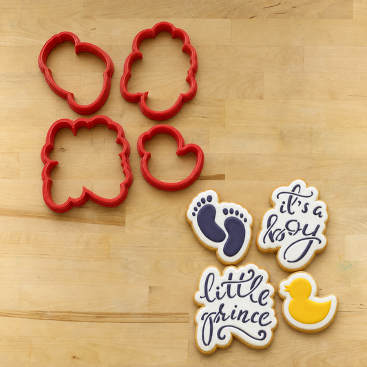 Cookies decorated with the "It's A Boy" Cookie Stencils lying next to the four matching 3D printed cookie cutters.