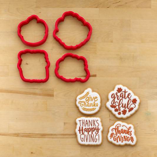 Four red cookie cutters arranged on a light wood surface, with four decorated cookies placed below them showing examples of the cutout shapes and fall-themed icing designs.