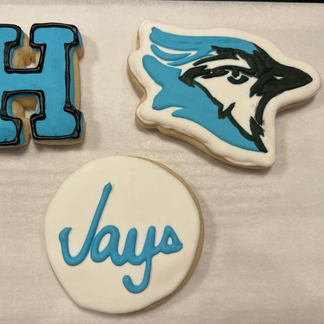 Three cookies with blue and black icing on a white surface