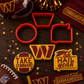 Set of cookie cutters and cookies with Washington Commanders branding on a wooden surface.
