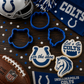 Indy Colts-themed cookies, cookie cutters, and sports memorabilia on a wooden surface.