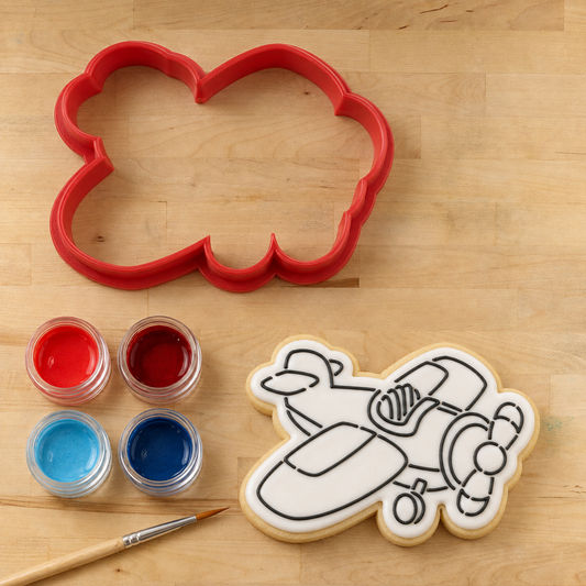 Airplane PYO Cookie Next to an Airplane PYO Cookie Cutter with food coloring and a food-safe paint brush.