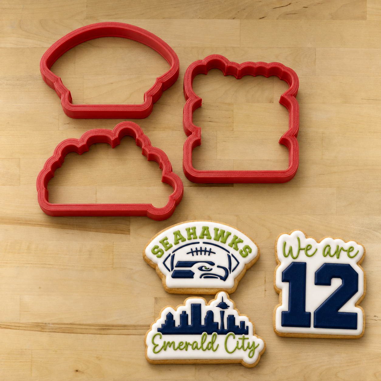 Seattle Seahawks Cookie Cutters lying next to three Seahawks themed cookies
