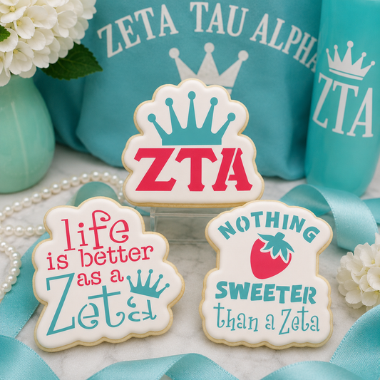 Three decorated ZTA-inspired sugar cookies with crown and strawberry designs displayed with turquoise sorority-themed décor.