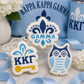Three decorated Kappa Kappa Gamma sugar cookies displayed with blue sorority-themed décor, ribbons, and floral accents.