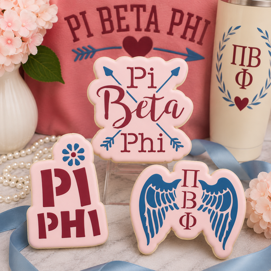 Three decorated Pi Beta Phi sugar cookies displayed with pink and blue sorority-themed décor, ribbons, and floral accents.