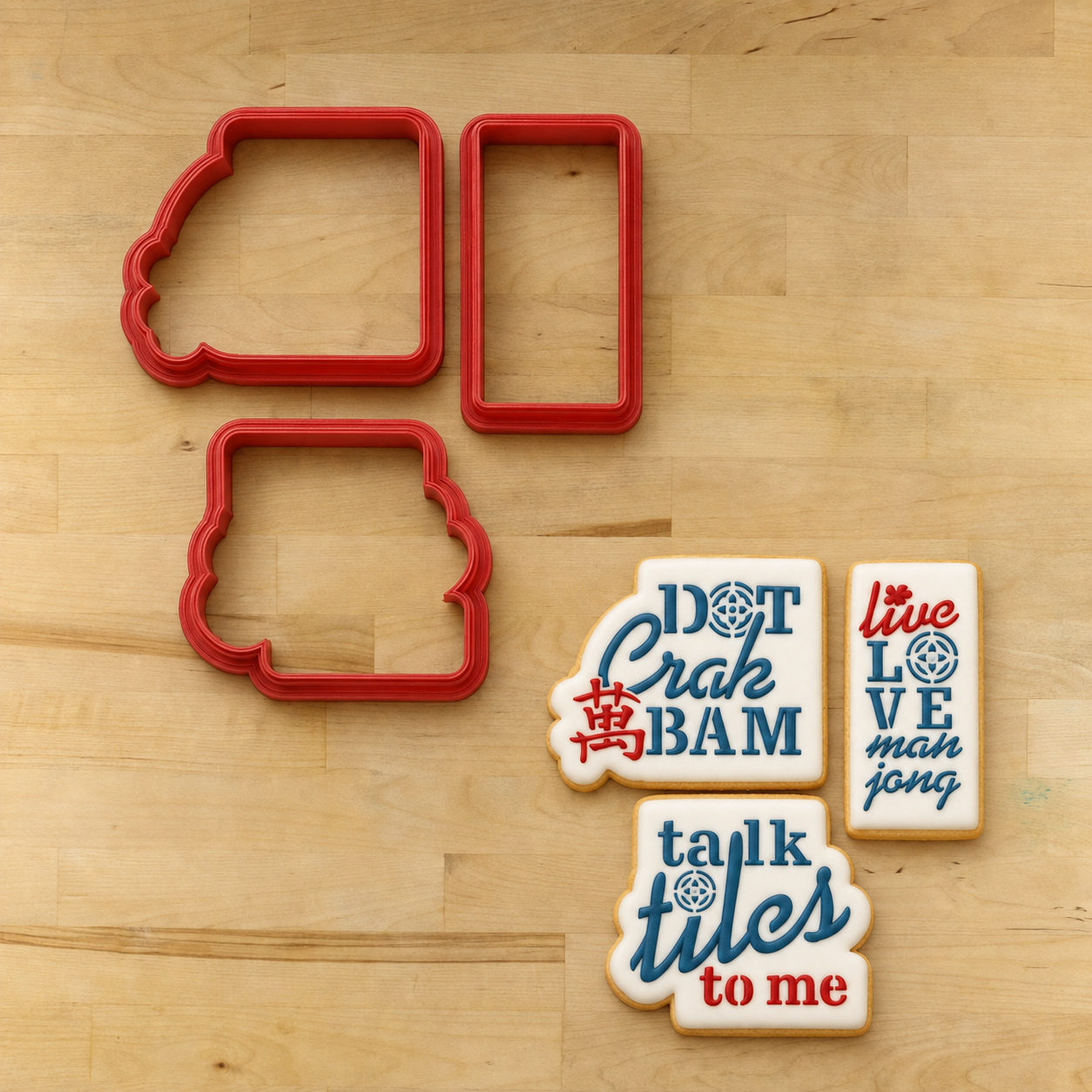 Three iced cookies stenciled with the Mahj Humor Cookie Stencil Set and three matching cookie cutters