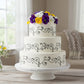 Two-tiered wedding cake with floral decorations on a wooden table.