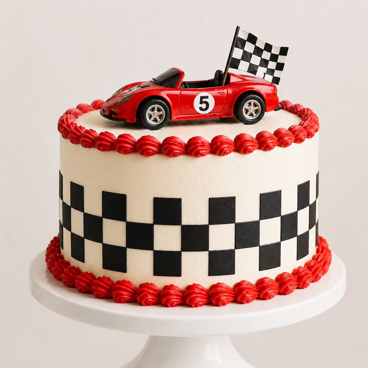 Cake decorated like a red race car with a checkered pattern on a white background