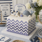 Nautical-themed baby shower cake with chevron pattern, whale figurine, and 'Ahoy! It's a Boy!' sign.