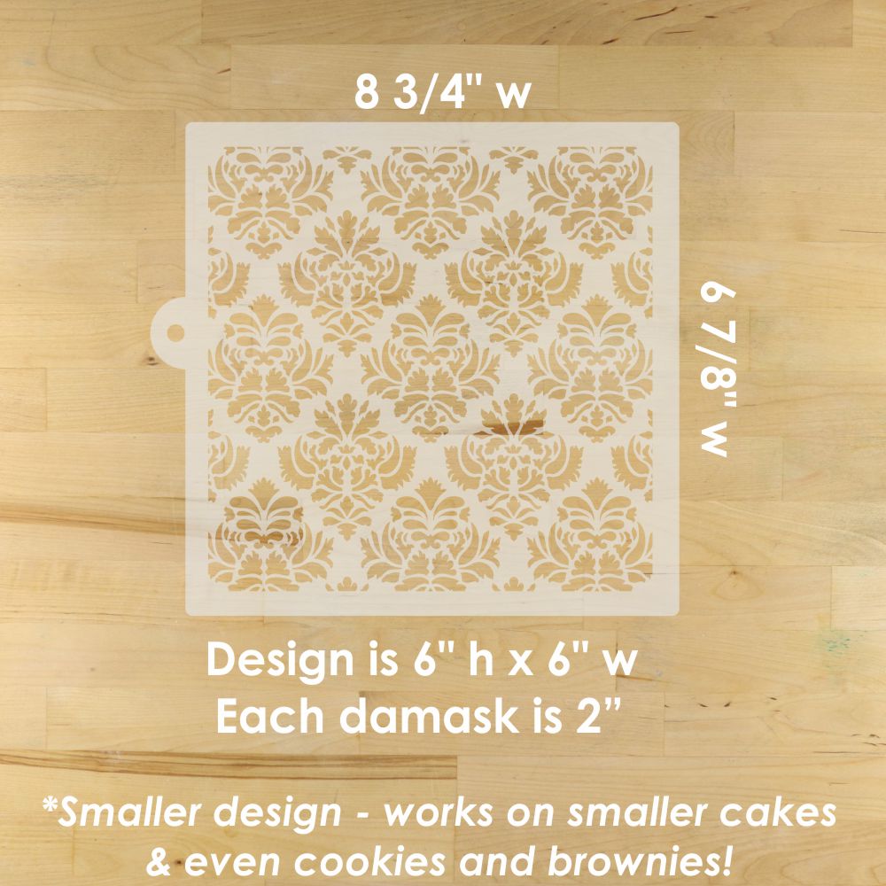 Decorative cake stencil with damask pattern on a wooden surface, showing measurements and design details.