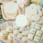 Collage of pastel green and white stenciled baby-themed treats including a cake, cookies, cupcakes, and macarons.