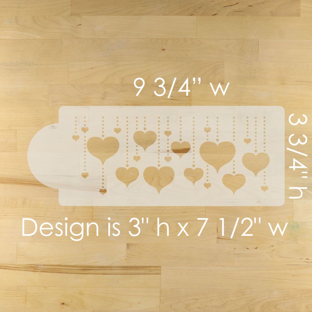 Cake stencil with heart designs on a wooden surface, showing measurements.