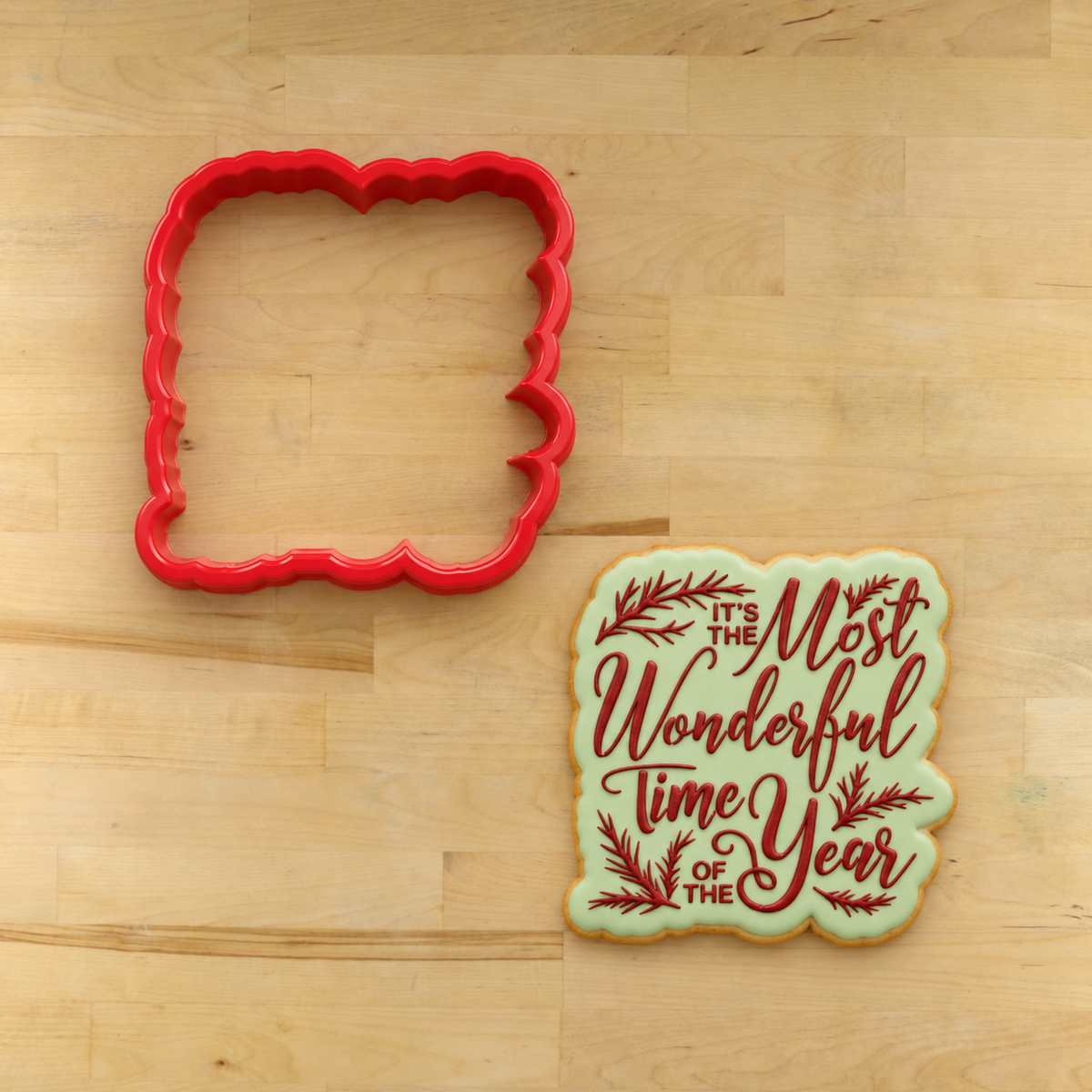 Cookie flooded and stenciled with the It's the Most Wonderful Time of the Year Cookie Stencil by Designer Stencils lying next to its matching cookie cutter.