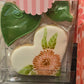 Heart-shaped cookie with floral design in a clear packaging sleeve.