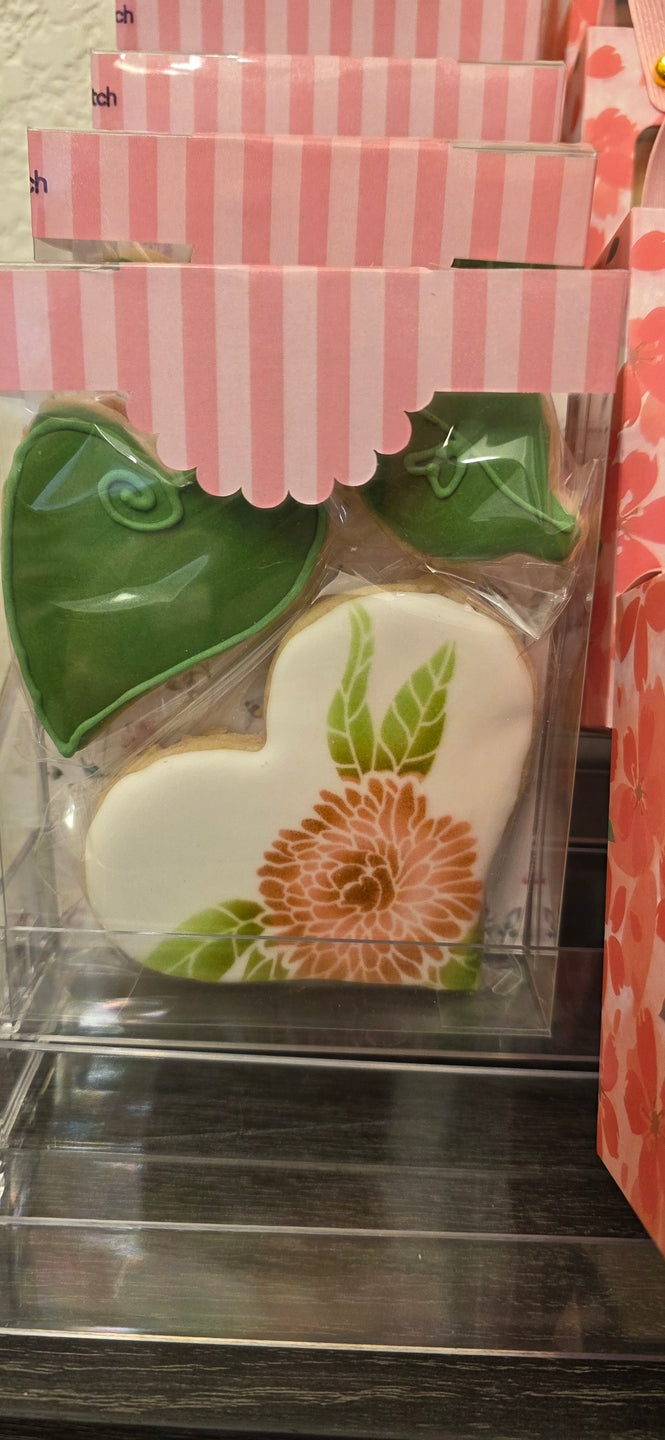 Heart-shaped cookie with floral design in a clear packaging sleeve.