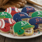 Decorative cookies shaped like baseball helmets and balls on a plate with sports-themed elements.