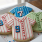 Decorative cookies shaped like baseball jerseys with numbers on a white plate.