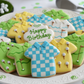 Decorative cookies shaped like shirts with 'Happy Birthday' text on a plate.