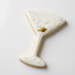 Cookie shaped like a martini glass with a olive on a white background